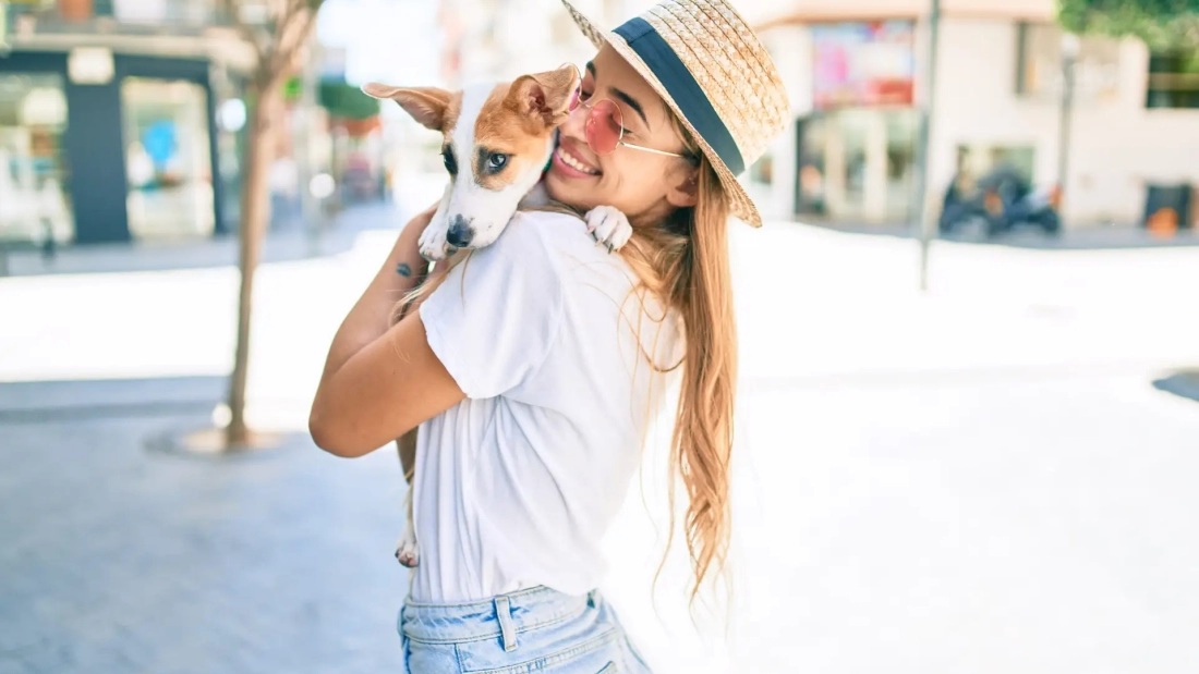 Young beautiful blonde woman hugging and cuddling puppy dog outdoors